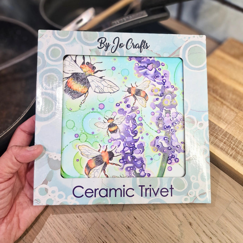 Bumblebee and Lavender ceramic trivet in By Jo Crafts gift box, held in hand, showing bumblebee and lavender design
