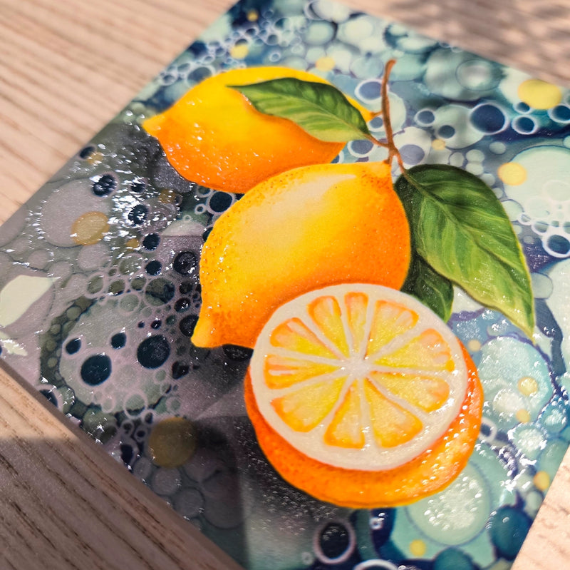 Close-up of lemon ceramic coaster showing embossed lemon design detail with teal bubble-effect background