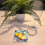 Lemon ceramic coaster on wooden table with wine glass beside fern plant, full coaster visible