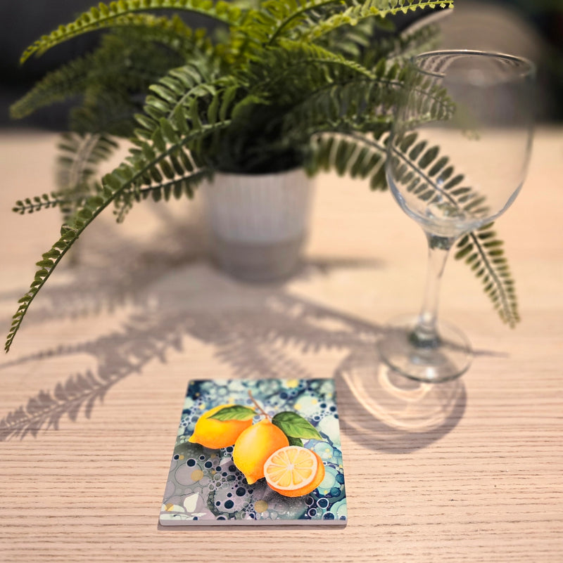 Lemon ceramic coaster on wooden table with wine glass beside fern plant, full coaster visible
