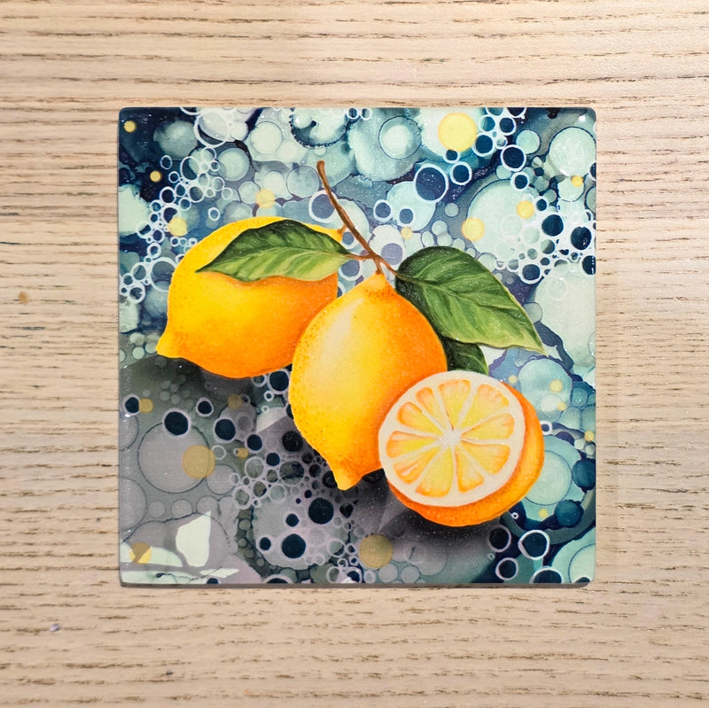 Lemon ceramic coaster flat lay on wooden surface showing full lemon design with teal bubble-effect background