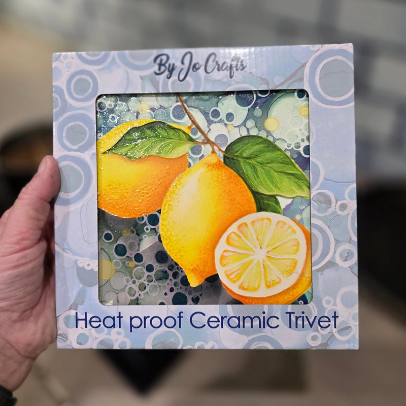 Lemon ceramic trivet in By Jo Crafts gift box showing lemon design with teal bubble-effect background
