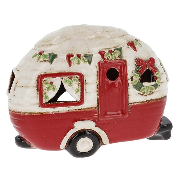 Village Pottery Christmas caravan tealight holder in white and red with holly and berry bunting, a door wreath and festive curtains in the window