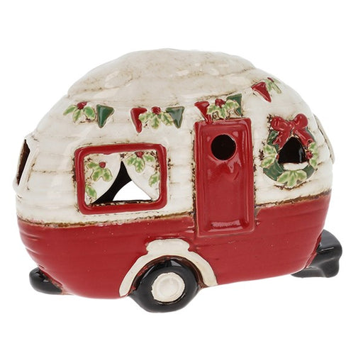 Village Pottery Christmas caravan tealight holder in white and red with holly and berry bunting, a door wreath and festive curtains in the window