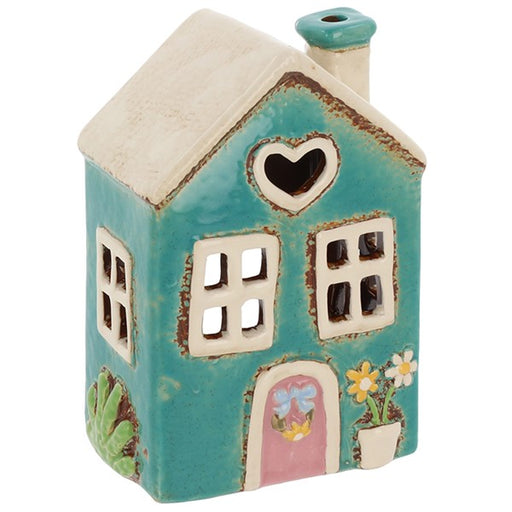 Handcrafted ceramic teal garden cottage tealight holder with pink arched door, heart-shaped window, yellow flower pot and cream roof with chimney, on a white background
