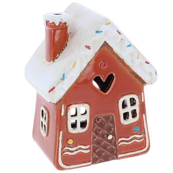 Village Pottery gingerbread house tealight holder with snow-dusted roof, colourful sprinkle details, heart cut-out above the door, waffle-pattern door with candy buttons, wavy icing trim, and side chimney