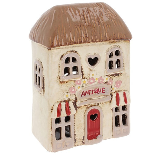Village Pottery Antique Shop ceramic tealight holder with red door, heart-shaped window, striped awnings and flower garland, front view on white background