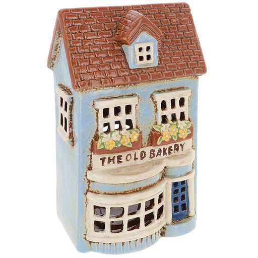 Village Pottery Old Bakery ceramic tealight holder with blue door, bay window and flower-filled window boxes, front view on white background