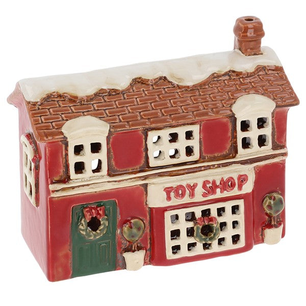 Village Pottery Christmas toy shop tealight house, red two-storey building with snow-dusted terracotta tiled roof, chimney, Toy Shop sign, large display window with wreath, green door with wreath and upper floor windows, white background