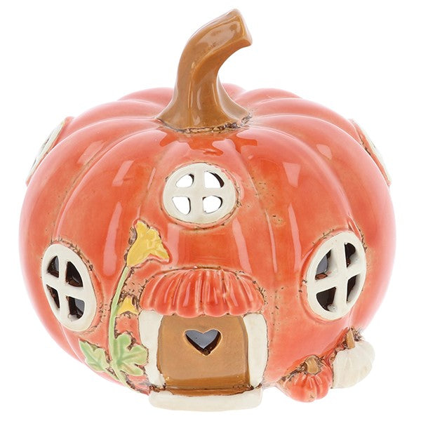 Village Pottery pumpkin house tealight holder — plump pumpkin with stalk, arched door with heart cut-out, cross-pattern windows, tall flower detail, and two mini pumpkins at the base