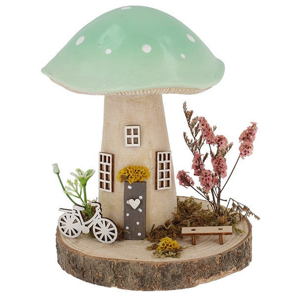 Spring Folk Art Mushroom House ornament with green pastel cap on wooden log base with miniature bicycle, bench and dried flowers