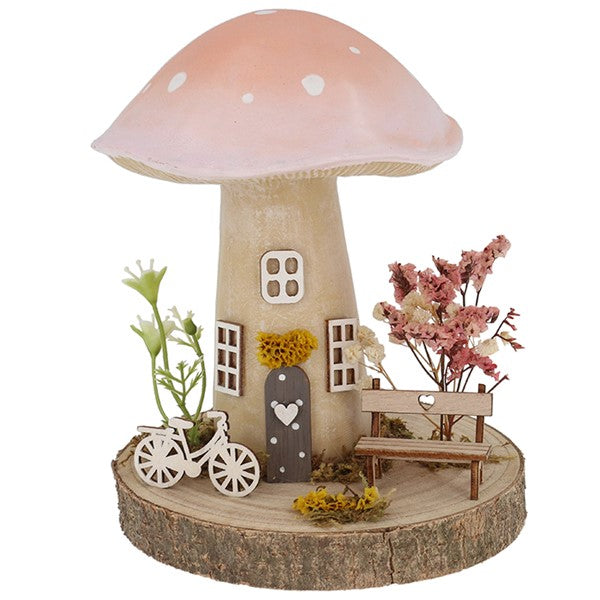 Spring Folk Art Mushroom House ornament with pink pastel cap on wooden log base with miniature bicycle, bench and dried flowers