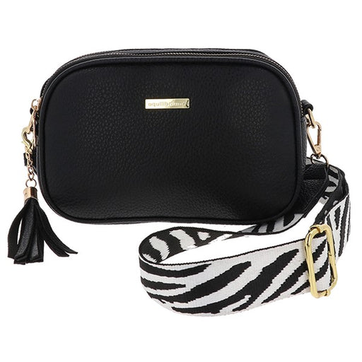 Equilibrium black faux leather crossbody bag with double zip, gold hardware, tassel detail and black and white zebra print wide strap, white background