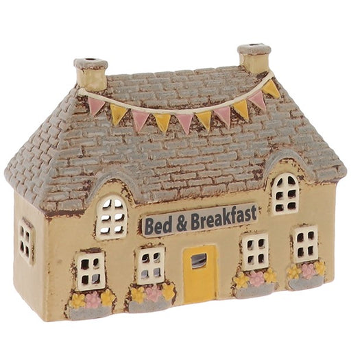 Village Pottery Bed & Breakfast ceramic tealight holder with yellow door, planters and decorative flags, front view on white background