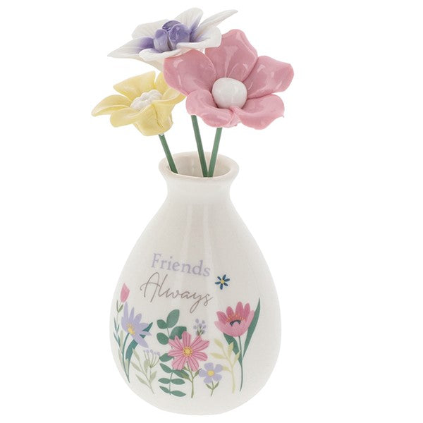 Friends Always flower vase angled view showing pastel blooms and wildflower illustration detail around the base of the white bud vase