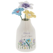 Home Sweet Home flower vase front view, white bottle-shaped vase with Home Sweet Home script and wildflower meadow illustration, three decorative flower stems in blue, purple and yellow