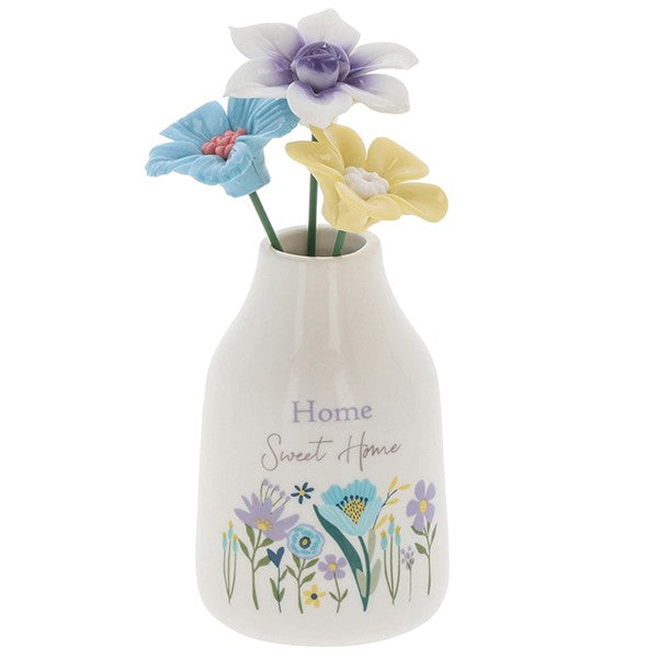 Home Sweet Home flower vase front view, white bottle-shaped vase with Home Sweet Home script and wildflower meadow illustration, three decorative flower stems in blue, purple and yellow