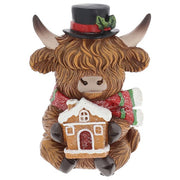 Merry Christmas Coos mini highland cow figurine wearing a black top hat with holly, holding a gingerbread house