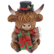 Merry Christmas Coos mini highland cow figurine wearing a black top hat with holly, holding a wrapped green gift with a red bow