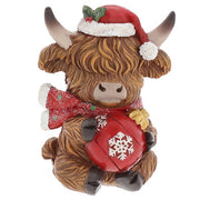 Merry Christmas Coos mini highland cow figurine wearing a Santa hat and red glittery scarf, holding a red bauble with snowflake detail