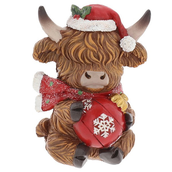 Merry Christmas Coos mini highland cow figurine wearing a Santa hat and red glittery scarf, holding a red bauble with snowflake detail
