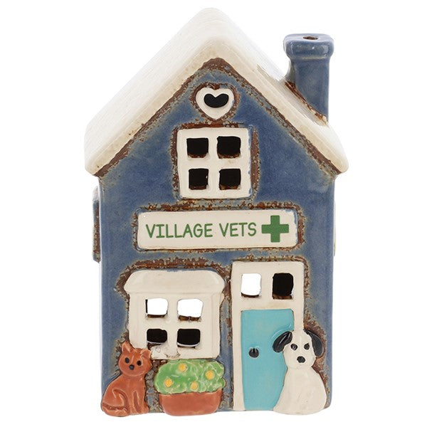 Front view of Village Pottery village vets tea light holder showing Village Vets signage with green cross, ginger cat, green plant pot and white dog detail 