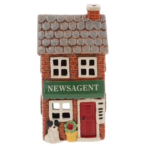 Front view of Village Pottery newsagent tea light holder showing Newsagent signage, cut-out windows and yellow flower pot with red flowers