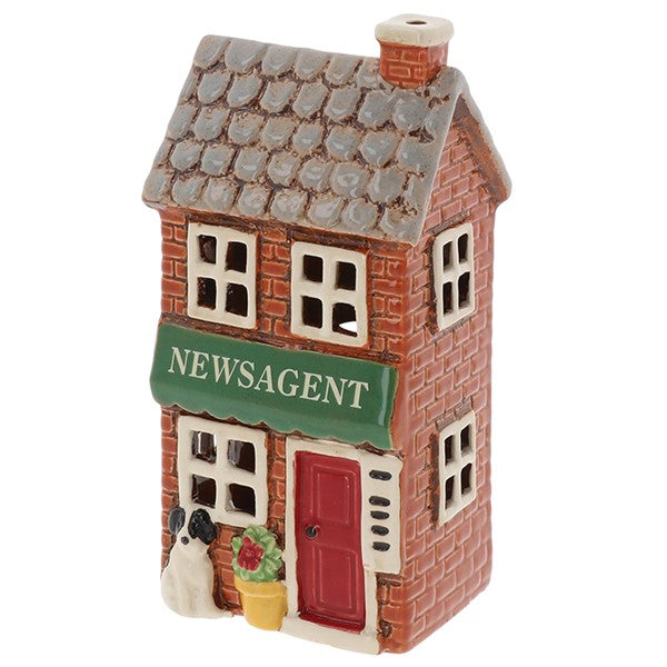 Village Pottery ceramic newsagent tea light holder, red brick-effect two-storey building with grey slate roof, green Newsagent awning, red door and black and white dog by the entrance