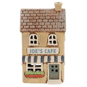 Front view of Village Pottery Joe's Cafe tea light holder showing blue-grey door, shop window cut-outs and window box with greenery