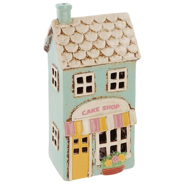 Three-quarter view of Village Pottery cake shop tea light holder showing full building detail, shop window cut-outs and Cake Shop signage