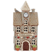 Village Pottery ceramic town hall tea light holder, warm stone brick-effect building with pointed clock tower, colourful bunting, dark brown arched door and two terracotta potted topiary trees