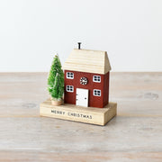 Quirky rust red wooden Christmas house decoration with natural wood roof, snowflake details, white windows and door, and snow-dusted bottle brush trees, 12cm⠋
