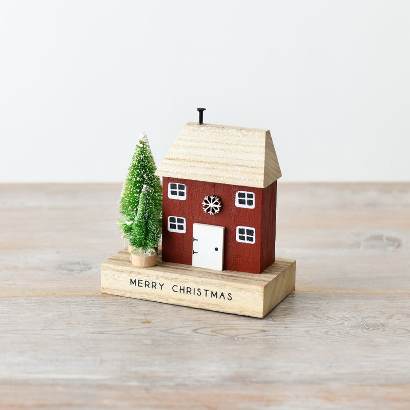 Quirky rust red wooden Christmas house decoration with natural wood roof, snowflake details, white windows and door, and snow-dusted bottle brush trees, 12cm⠋