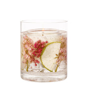 Close-up of Stoneglow Nature's Gift Apple and Pear Blossom botanical candle in straight-sided glass tumbler showing dried botanicals and fruit slices with lit wick