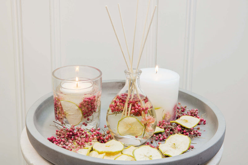 Stoneglow Nature's Gift Apple and Pear Blossom botanical candle and reed diffuser styled together on grey tray with dried botanicals and fruit slices
