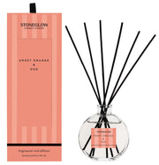 Stoneglow Modern Classics Sweet Orange and Oud Reed Diffuser in globe glass vessel with black reeds, shown with coral gift box
