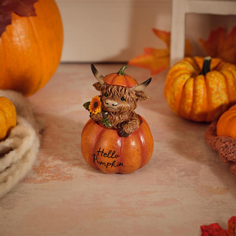 Highland cow figurine sitting inside a pumpkin wearing a pumpkin hat and holding a sunflower, with "Hello Pumpkin" inscription on the front, 9.5 x 9 x 12.5cm