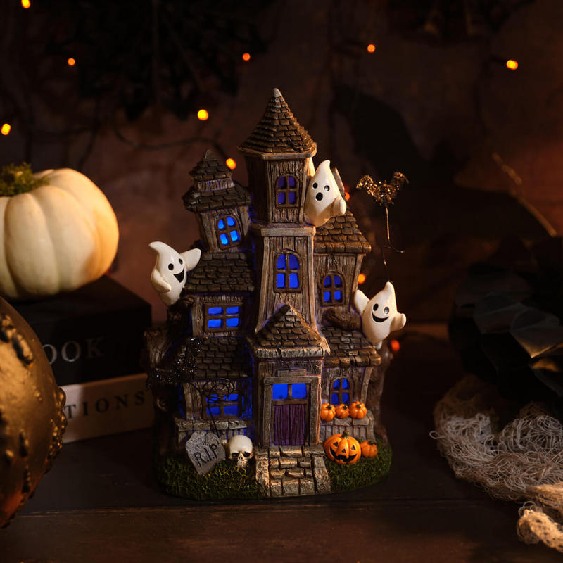 Tall Halloween haunted house decoration with friendly ghosts, jack-o'-lanterns, bat and skull details, with multicoloured LED glowing windows and door, 17.5 x 13 x 25.5cm