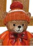 Pumpkin bear shelf sitter ornament wearing a knitted bobble hat with red bow and dangly rope legs, close-up detail