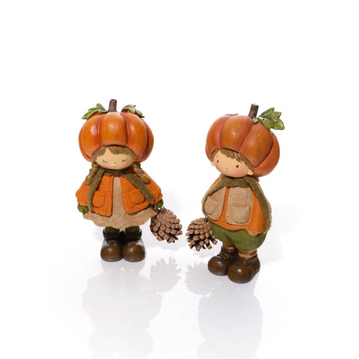 Two resin pumpkin figurines on a white background — a girl with plaited hair in a textured top and lace-trim skirt, and a boy in a textured gilet and trousers, each wearing a pumpkin hat with stalk and leaf detail and holding a pinecone