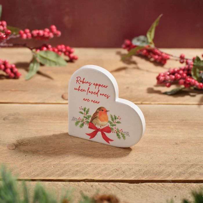 Robins appear when loved ones are near" white heart decoration with robin and holly illustration, styled on wooden surface with red berry branches