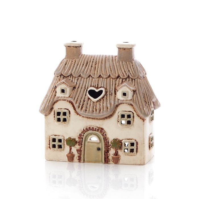 Front view of cream stoneware thatched cottage tealight holder showing embossed roof, arched door and heart cutout, Stoneware Country Cottage Collection