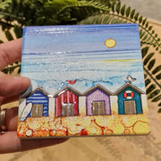 4 Beach Huts ceramic coaster held in hand showing close-up of embossed beach hut design with glitter detail and sparkling textured sea