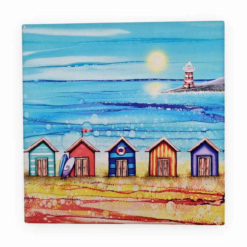 5 Beach Huts and Lighthouse ceramic trivet flat lay on white background showing full design with five colourful beach huts, surfboard, life ring, red flag and lighthouse with sparkling textured sea