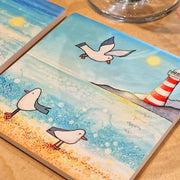 Close-up of Seagull and Lighthouse ceramic coaster design detail showing seagull on sandy beach with lighthouse in background
