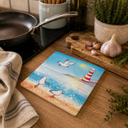 Seagull and Lighthouse ceramic trivet shown on wooden kitchen worktop beside a pan