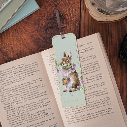 Wrendale Designs Head Clover Heels rabbit bookmark placed in an open book on a wooden desk alongside stationery and a glass of water