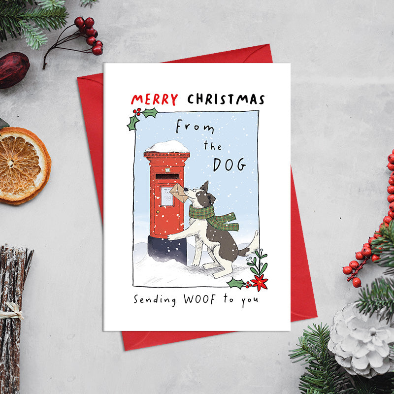 From the Dog Christmas card featuring an illustrated dog wearing a scarf and holding an envelope beside a snowy postbox, with the greeting ‘Sending WOOF to you
