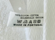 Care label showing 100% cotton, machine washable at 40 degrees, made in Portugal