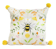 Bee Meadow Embroidered Cushion with large central embroidered bumblebee with yellow and black striped body and white wings, bee and meadow flower design in yellows and whites with green foliage on natural linen-mix background with yellow pom pom in each corner, 45 x 45 cm, on white background